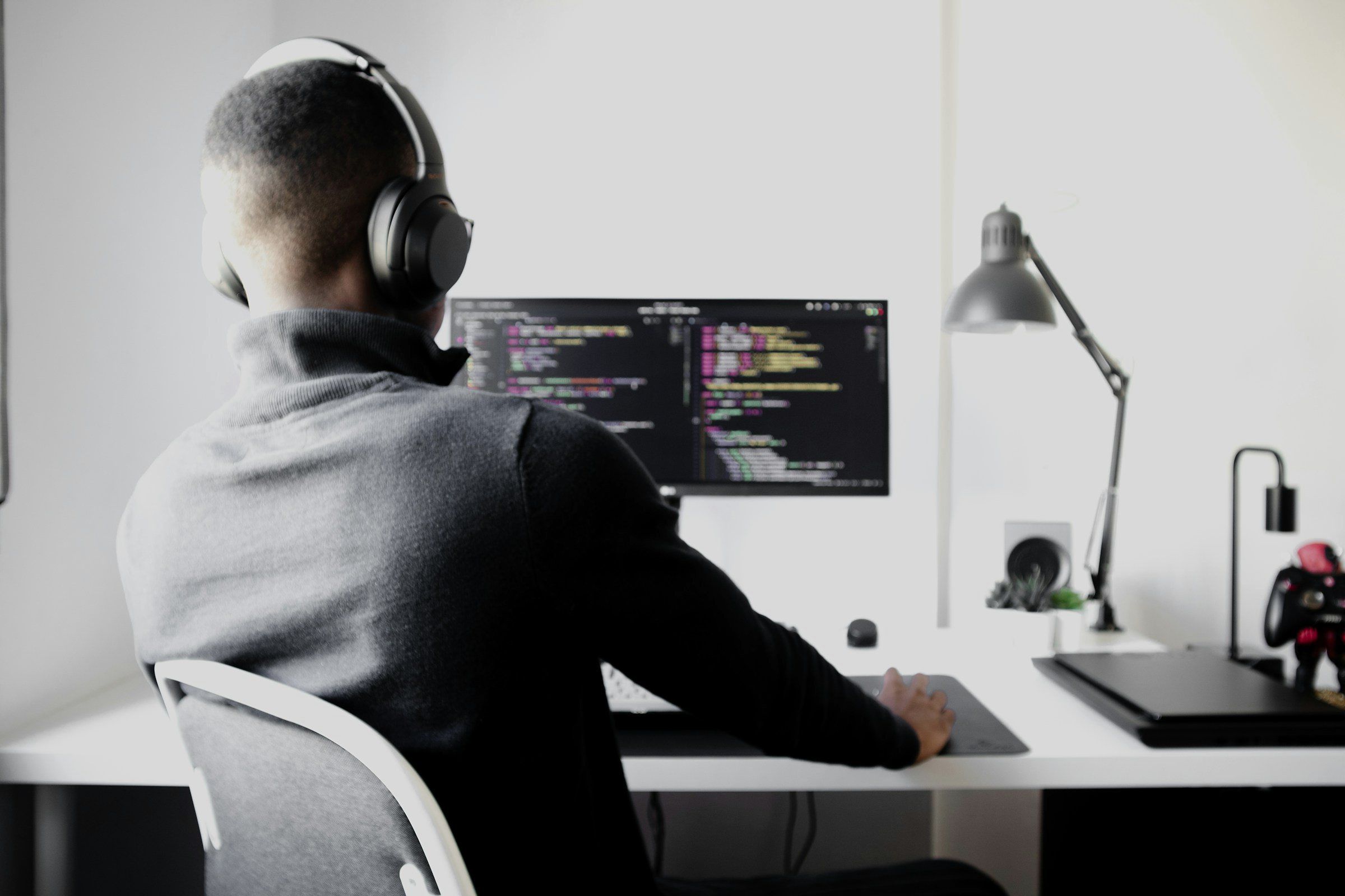 Entwickler mit Kopfhörern vor einem Bildschirm mit Quellcode